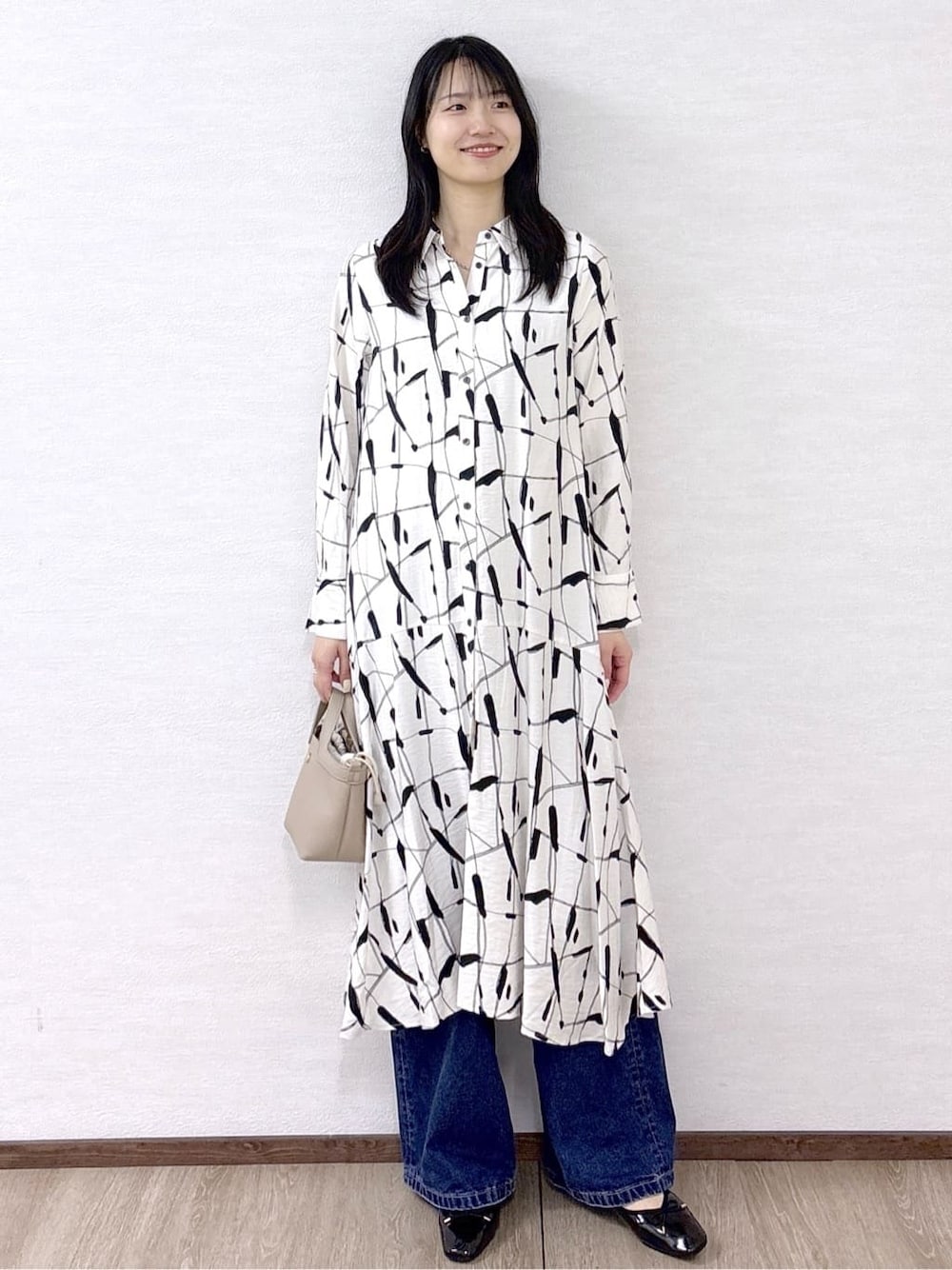 ベージュ系のワンピース、ブルー系のデニムパンツ、ベージュ系のショルダーバッグを着用したレディースの春コーディネートの8枚目の写真