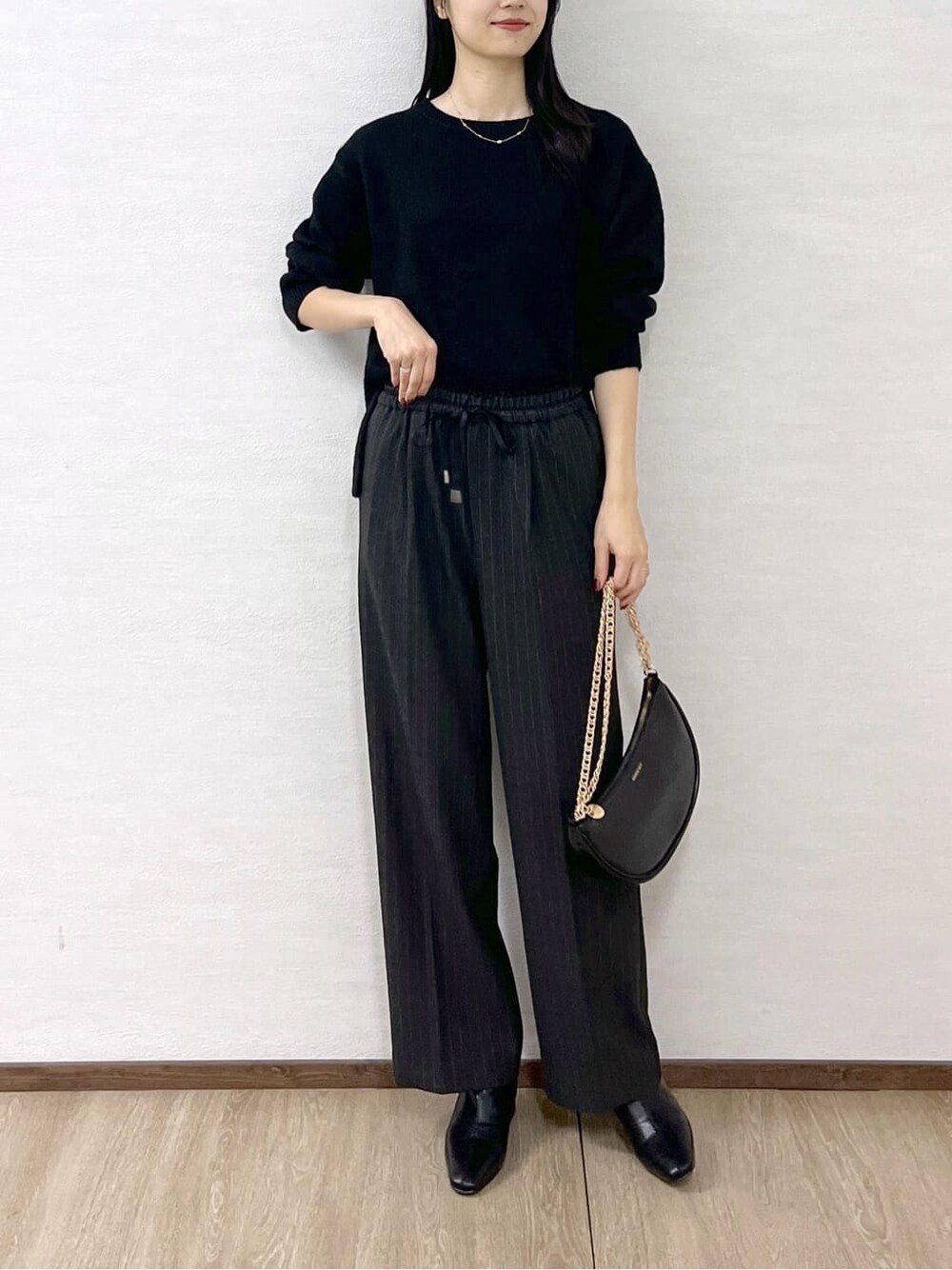 ブラック系のニット/セーター、グレー系のその他パンツ、ブラック系のハンドバッグを着用したレディースの冬コーディネートの7枚目の写真