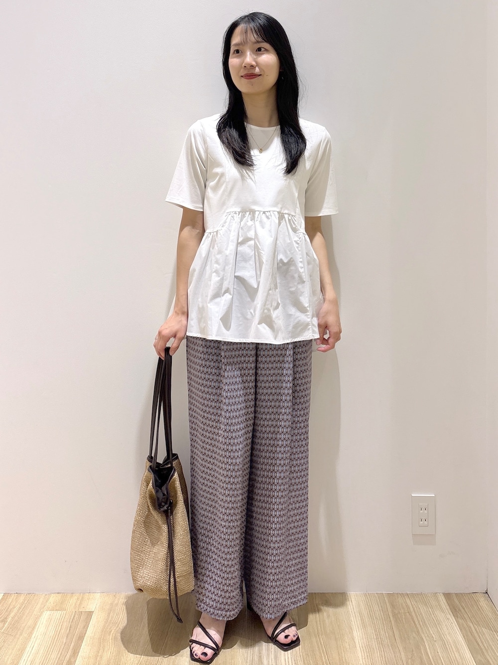 ブラウン系のサンダル、ベージュ系のトートバッグ、ホワイト系のTシャツ/カットソーを着用したレディースの春コーディネートの2枚目の写真