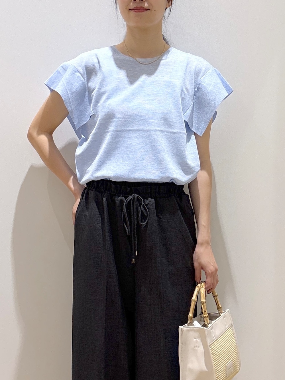 ブルー系のニット/セーター、グレー系のその他パンツ、ホワイト系のトートバッグを着用したレディースの夏コーディネートの6枚目の写真