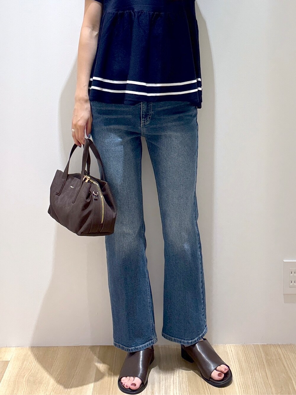 ブルー系のニット/セーター、ブルー系のデニムパンツ、ブラウン系のボストンバッグを着用したレディースの夏コーディネートの7枚目の写真