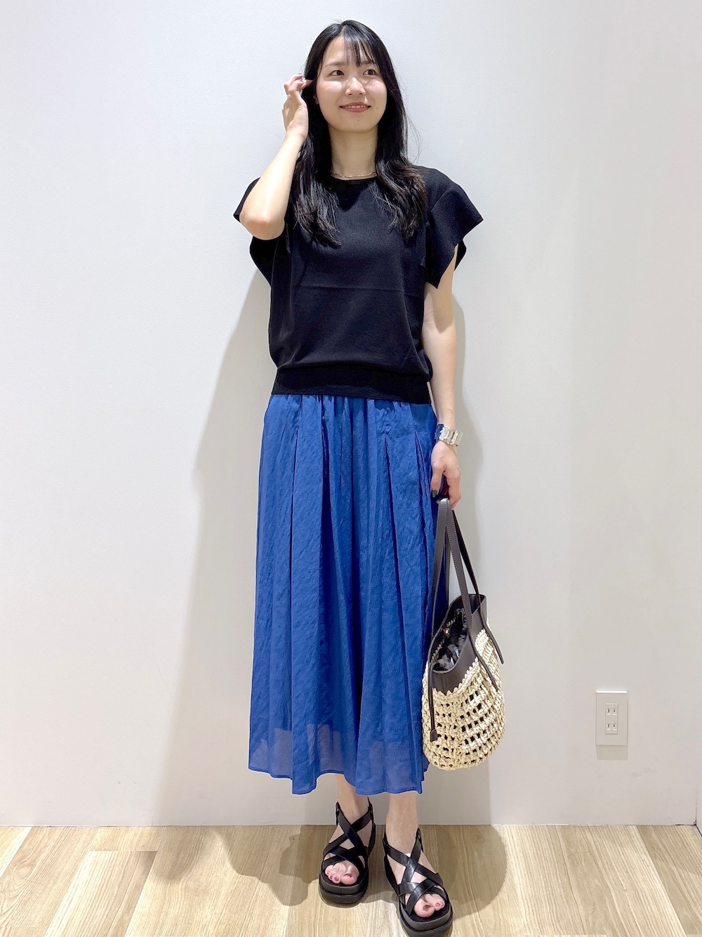 ブラック系のニット/セーター、ブルー系のその他パンツ、ブラウン系のトートバッグを着用したレディースの夏コーディネートの2枚目の写真