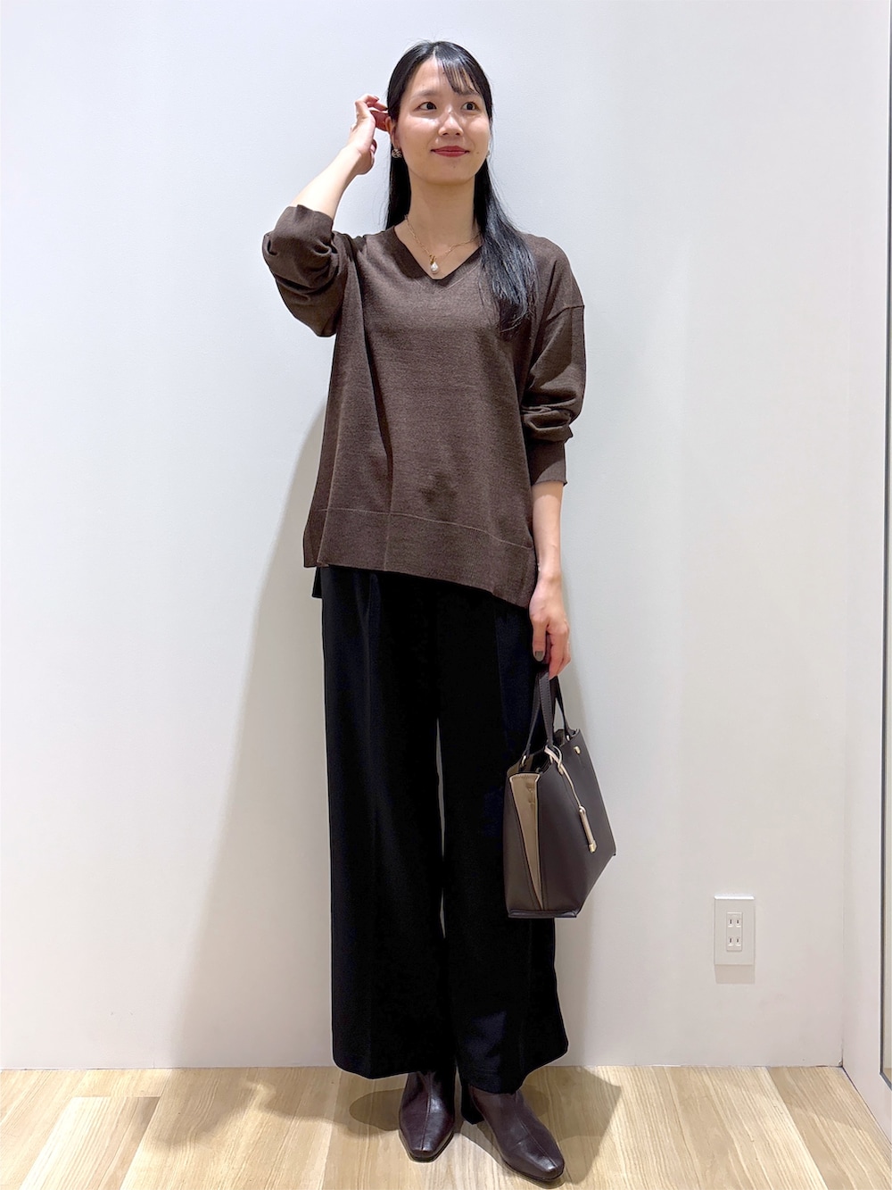 ブラウン系のニット/セーター、ブラック系のその他パンツ、ブラウン系のトートバッグを着用したレディースの秋コーディネートの2枚目の写真