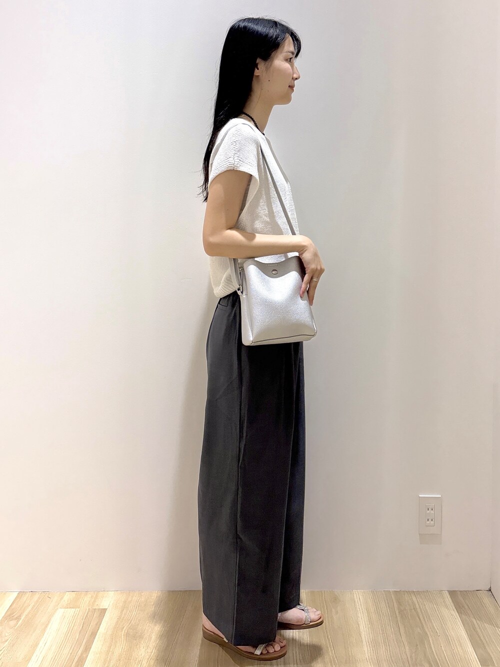 ホワイト系のニット/セーター、グレー系のその他パンツ、シルバー系のショルダーバッグを着用したレディースの夏コーディネートの5枚目の写真