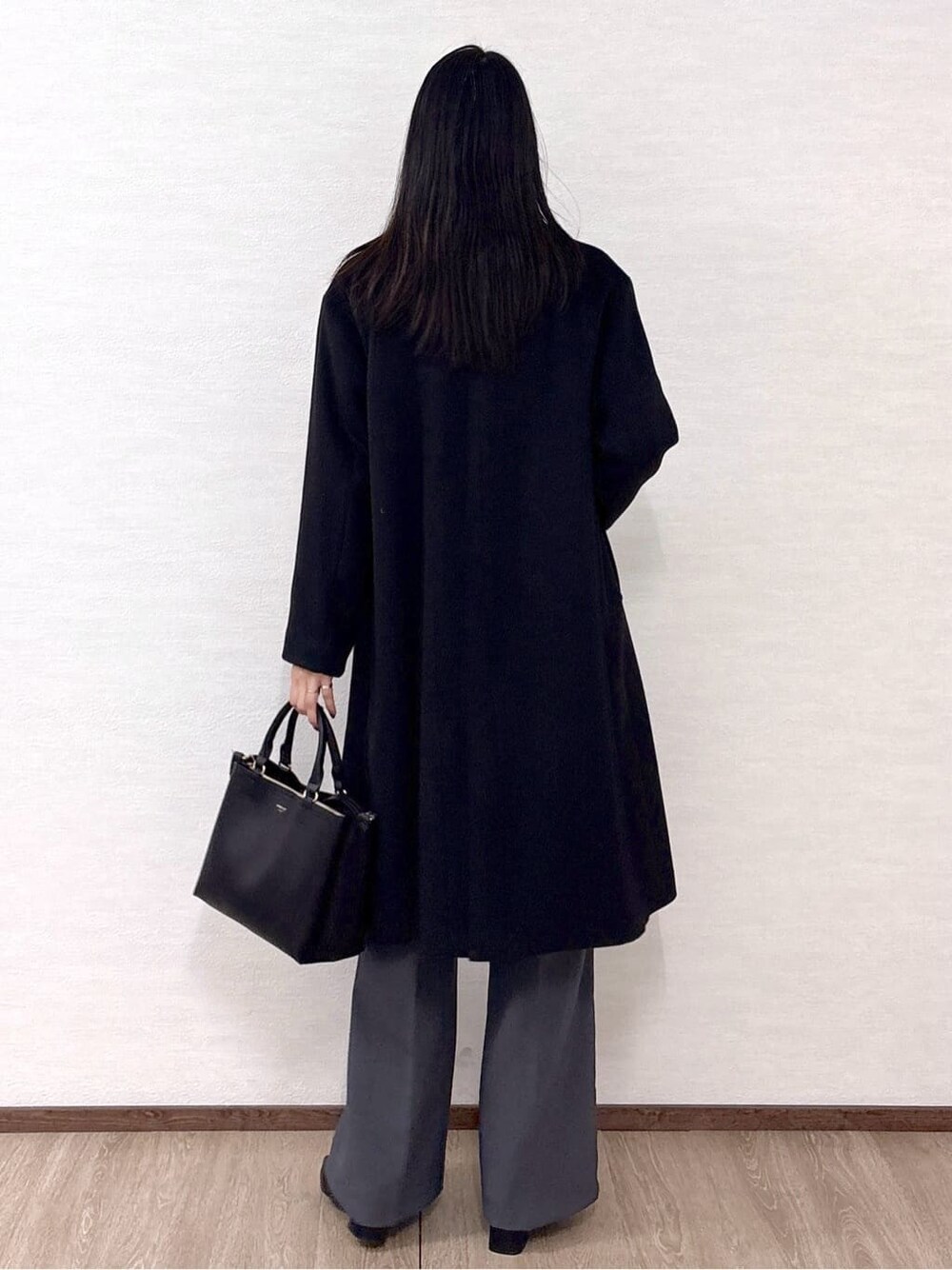 ブラック系のチェスターコート、ブルー系のニット/セーター、グレー系のその他パンツを着用したレディースの冬コーディネートの4枚目の写真