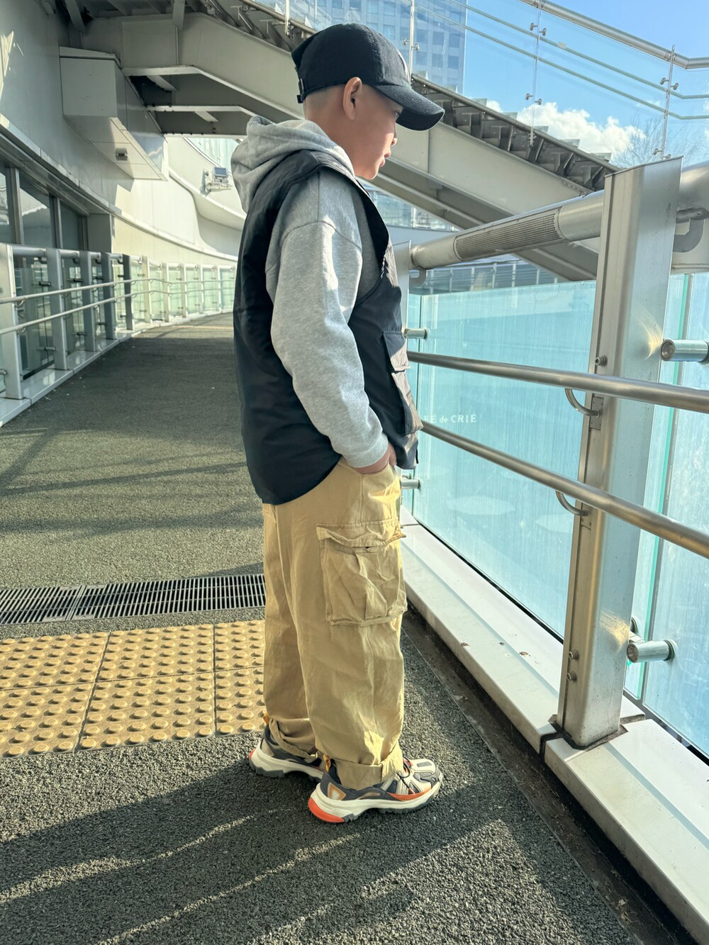 ブラック系のブルゾン、ベージュ系のカーゴパンツ、グリーン系のスニーカーを着用したキッズの春コーディネートの2枚目の写真