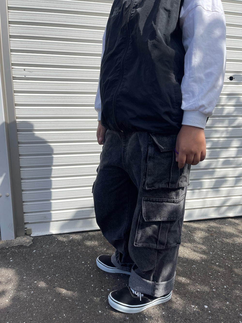 ブラック系のダウンベスト、ブラック系のデニムパンツ、オレンジ系のニットキャップ/ビーニーを着用したキッズの秋コーディネートの2枚目の写真