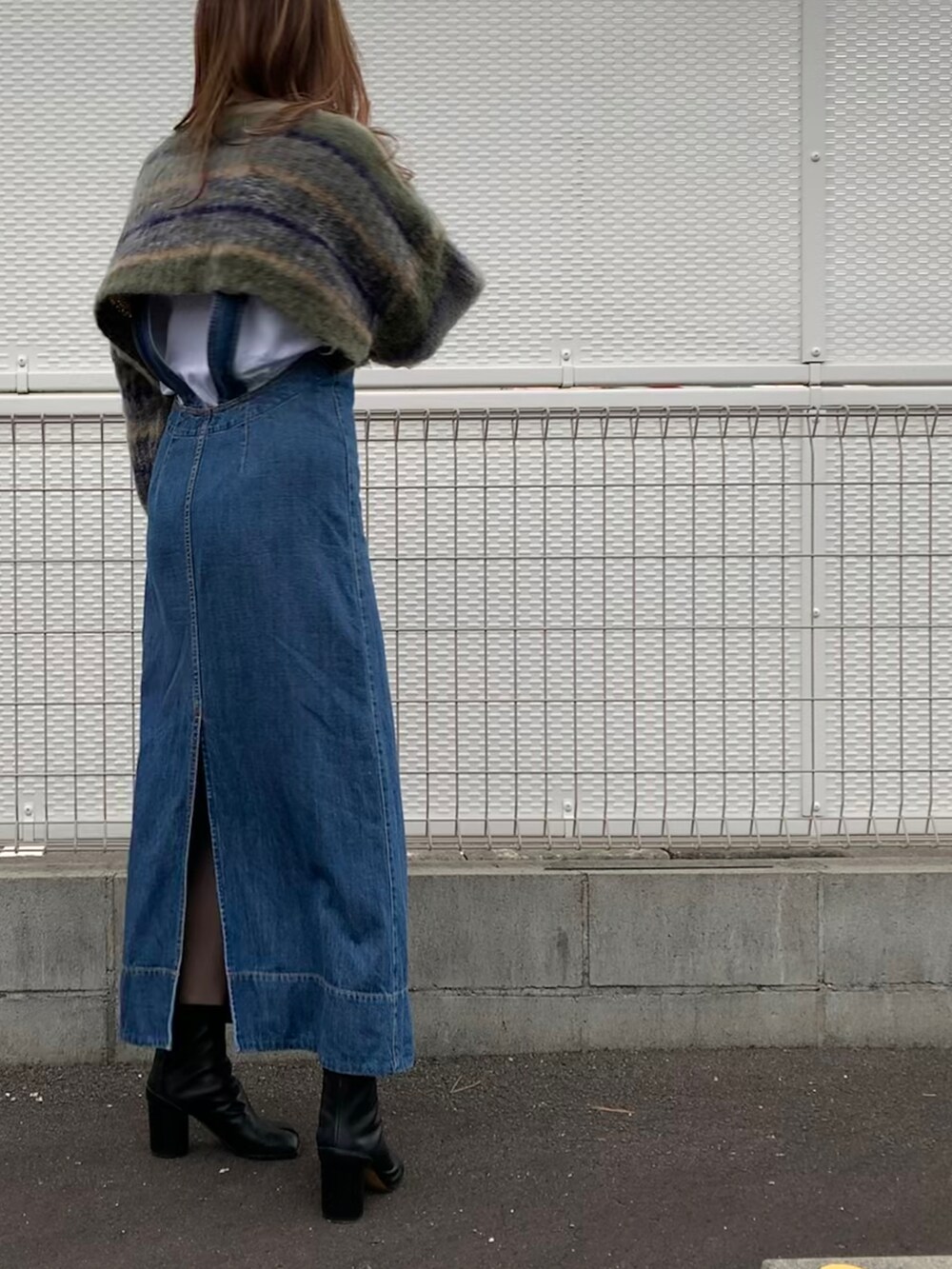 グリーン系のニット/セーター、ブルー系のジャンパースカート、ブラック系のボストンバッグを着用したレディースの春コーディネートの2枚目の写真