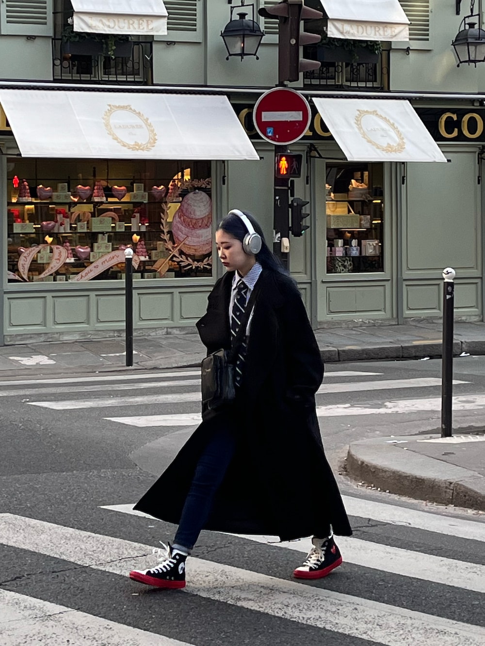 ブラック系のチェスターコート、ブラック系のショルダーバッグ、ブラック系のスニーカーを着用したレディースの冬コーディネートの2枚目の写真