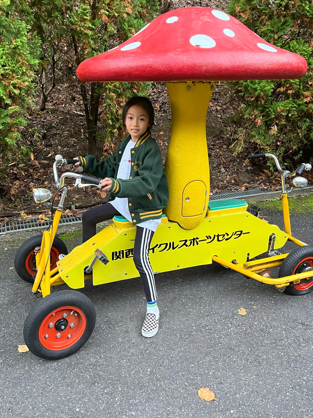 グリーン系のスタジャン、ブラック系のスリッポン、ブラック系のレギンス/スパッツを着用したキッズの秋コーディネートの2枚目の写真