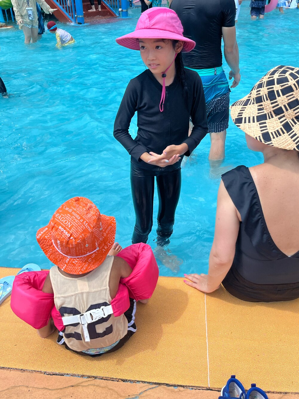 ブラック系のビーチサンダル、ピンク系のワンピース、ピンク系の帽子を着用したキッズの夏コーディネートの3枚目の写真