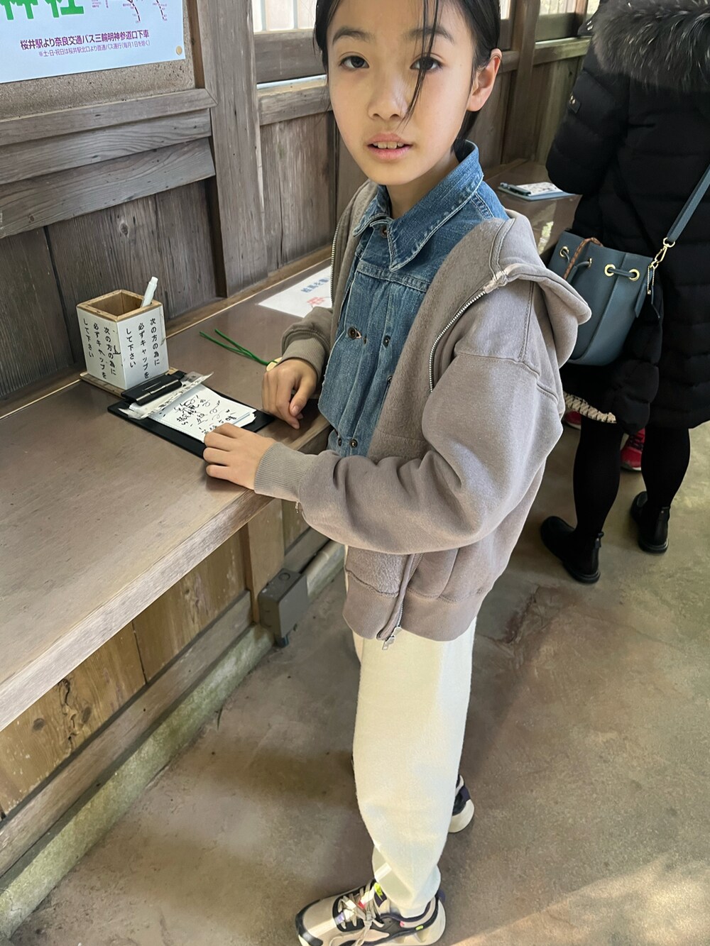 ホワイト系のスウェットパンツ、ブルー系のデニムジャケット、グレー系のパーカーを着用したキッズの冬コーディネートの2枚目の写真