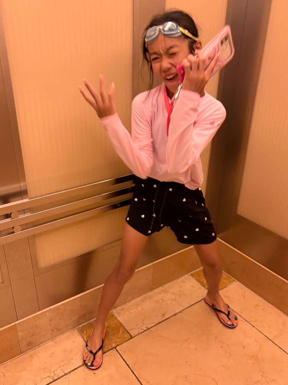 ピンク系のラッシュガード、ブラック系の水着を着用したキッズの夏コーディネートの5枚目の写真