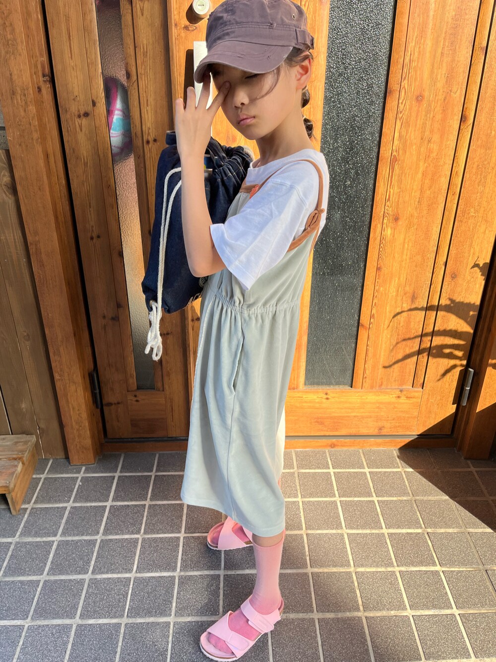 ピンク系のサンダル、グリーン系のワンピース、ホワイト系のTシャツ/カットソーを着用したキッズの春コーディネートの2枚目の写真