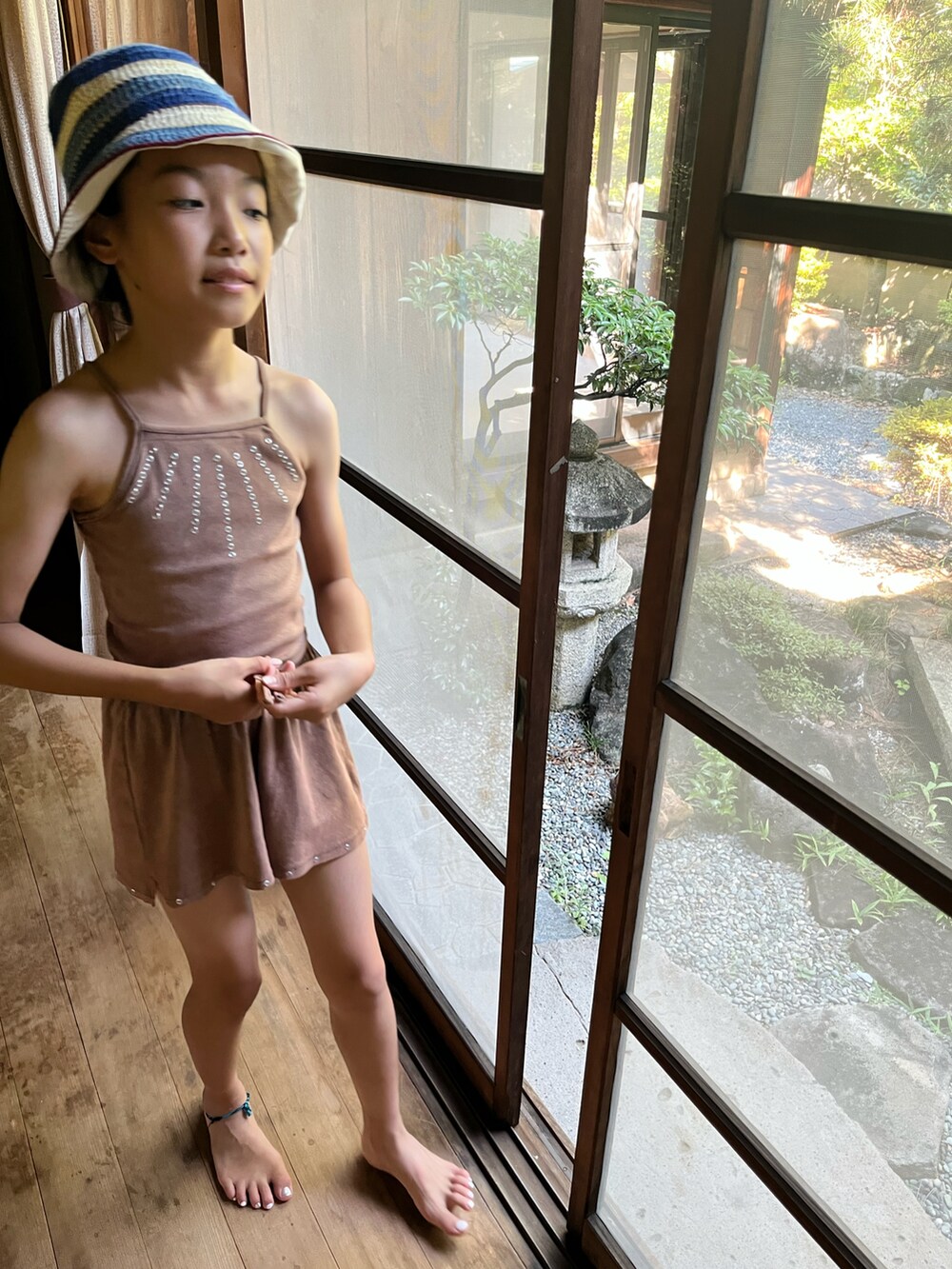 ブラウン系のタンクトップ、ブラウン系のパンツ、ピンク系のサンダルを着用したキッズの夏コーディネートの2枚目の写真