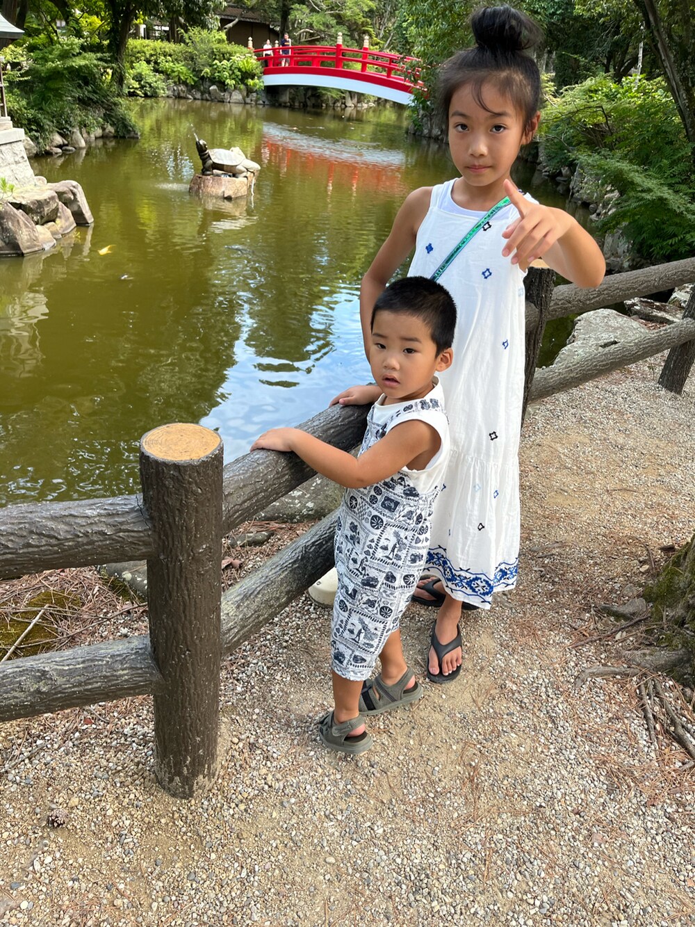 ホワイト系のワンピース、ブラック系のビーチサンダル、ブルー系のショルダーバッグを着用したキッズの夏コーディネートの2枚目の写真