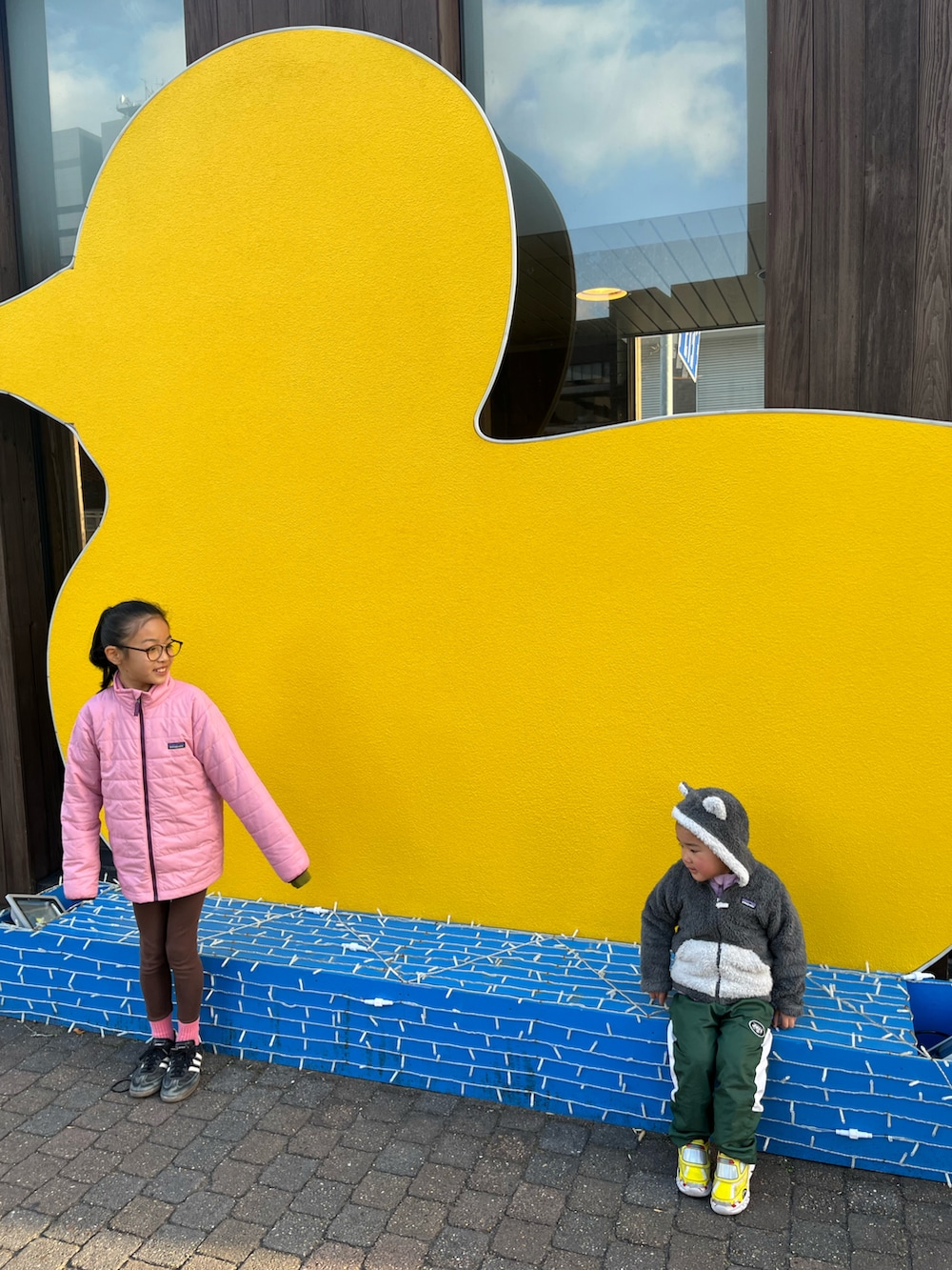 ブラック系のスニーカー、ピンク系のナイロンジャケット、ブラウン系のレギンス/スパッツを着用したキッズの冬コーディネートの2枚目の写真