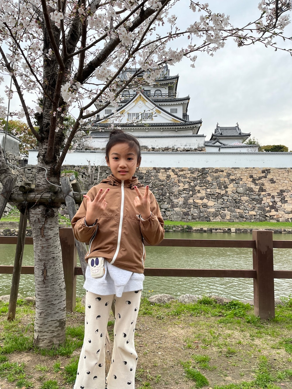 グレー系のスウェット、ブラウン系のナイロンジャケット、ホワイト系のその他パンツを着用したキッズの春コーディネートの2枚目の写真