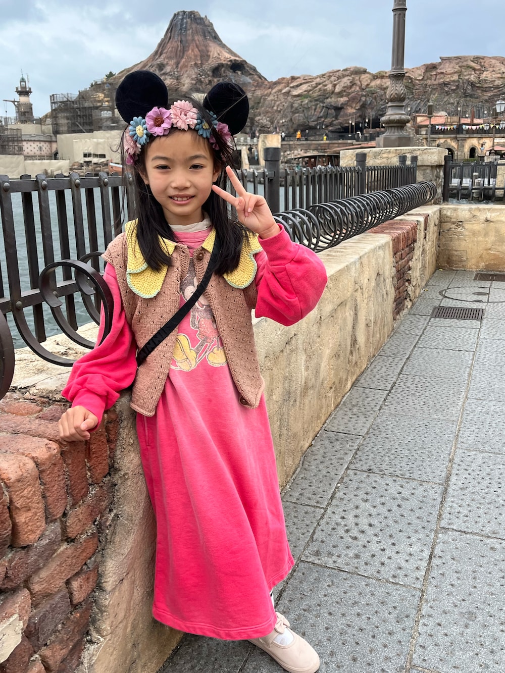 ピンク系のワンピース、ベージュ系のスリッポン、ブラウン系のベストを着用したキッズの春コーディネートの2枚目の写真