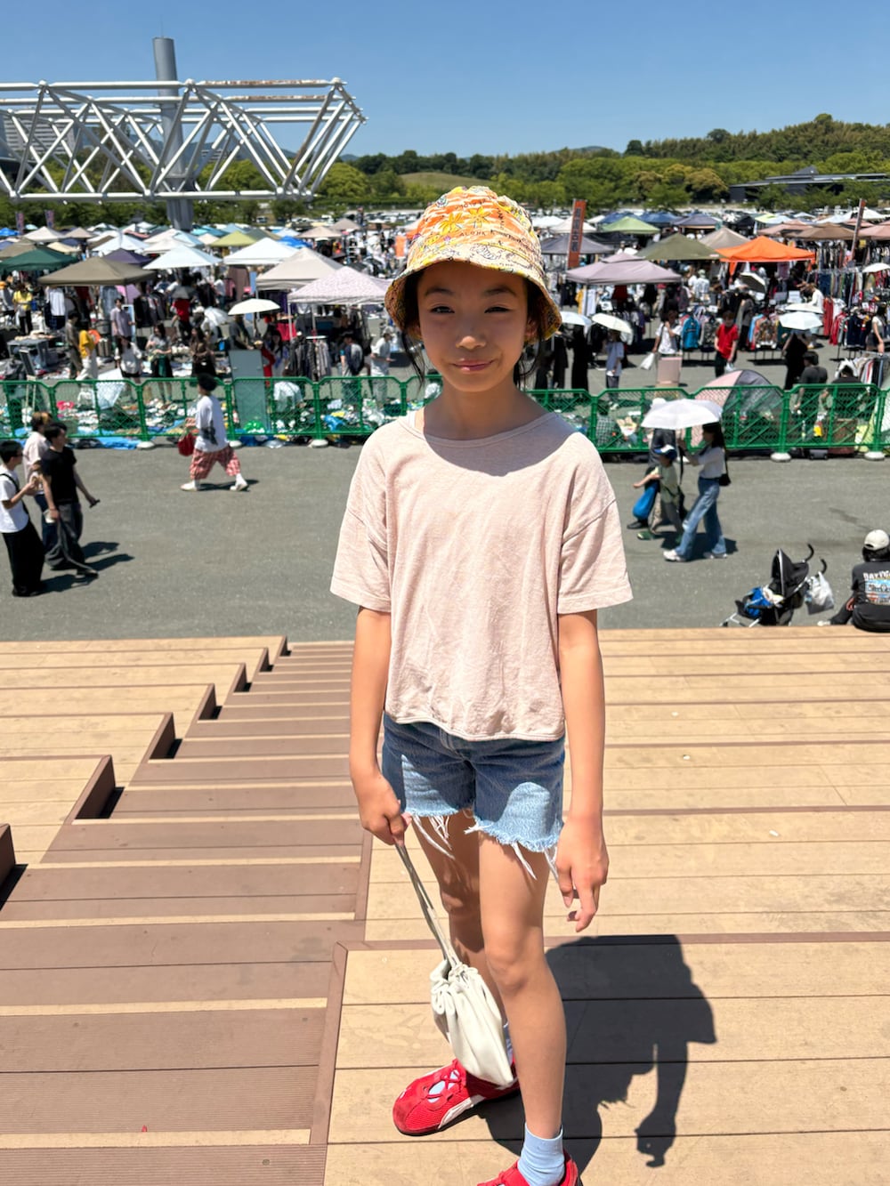 ピンク系のTシャツ/カットソー、ブルー系のデニムパンツ、レッド系のスニーカーを着用したキッズの春コーディネートの3枚目の写真