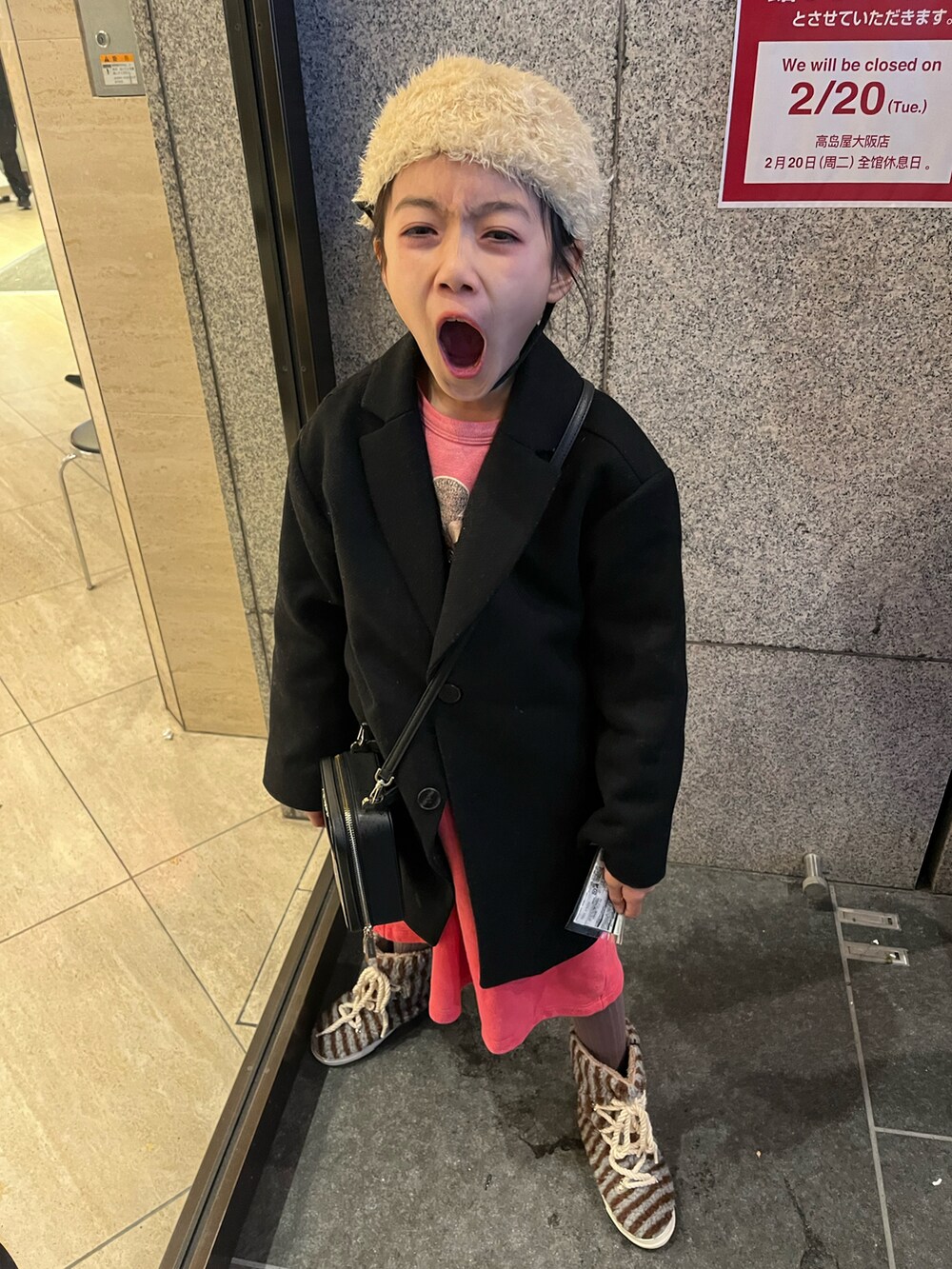 ブラック系のチェスターコート、ブルー系のブーツ、ブラック系のショルダーバッグを着用したキッズの冬コーディネートの3枚目の写真