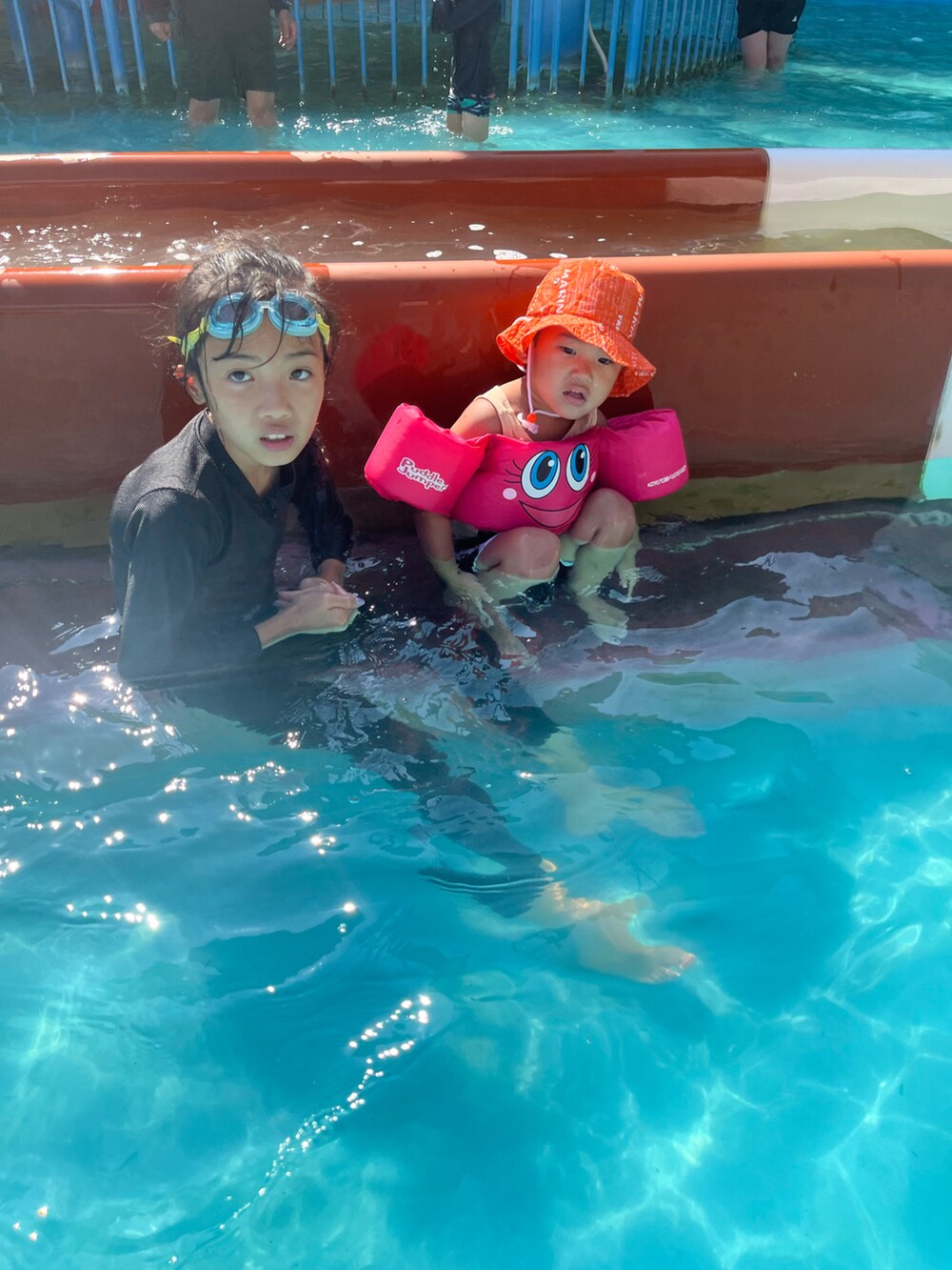 ブラック系のビーチサンダル、ピンク系のワンピース、ピンク系の帽子を着用したキッズの夏コーディネートの4枚目の写真