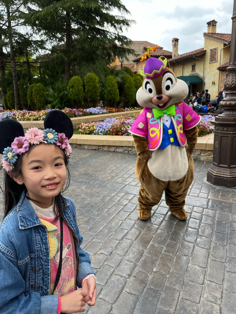 ピンク系のワンピース、ベージュ系のスリッポン、ブラウン系のベストを着用したキッズの春コーディネートの3枚目の写真