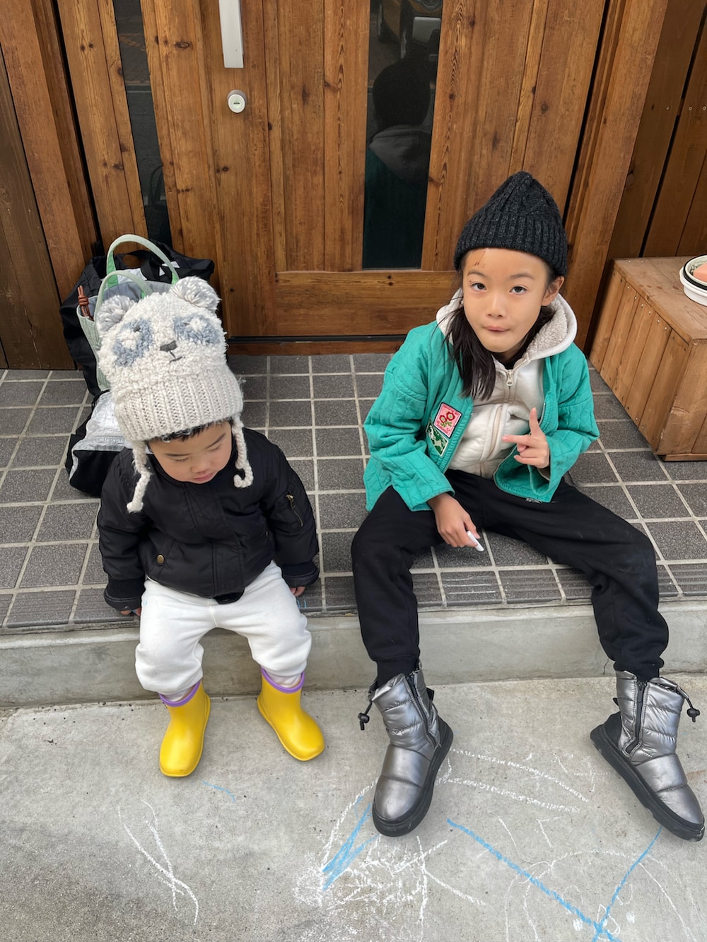 グリーン系のノーカラーコート、ベージュ系のスウェット、ブラック系のスウェットパンツを着用したキッズの冬コーディネートの2枚目の写真