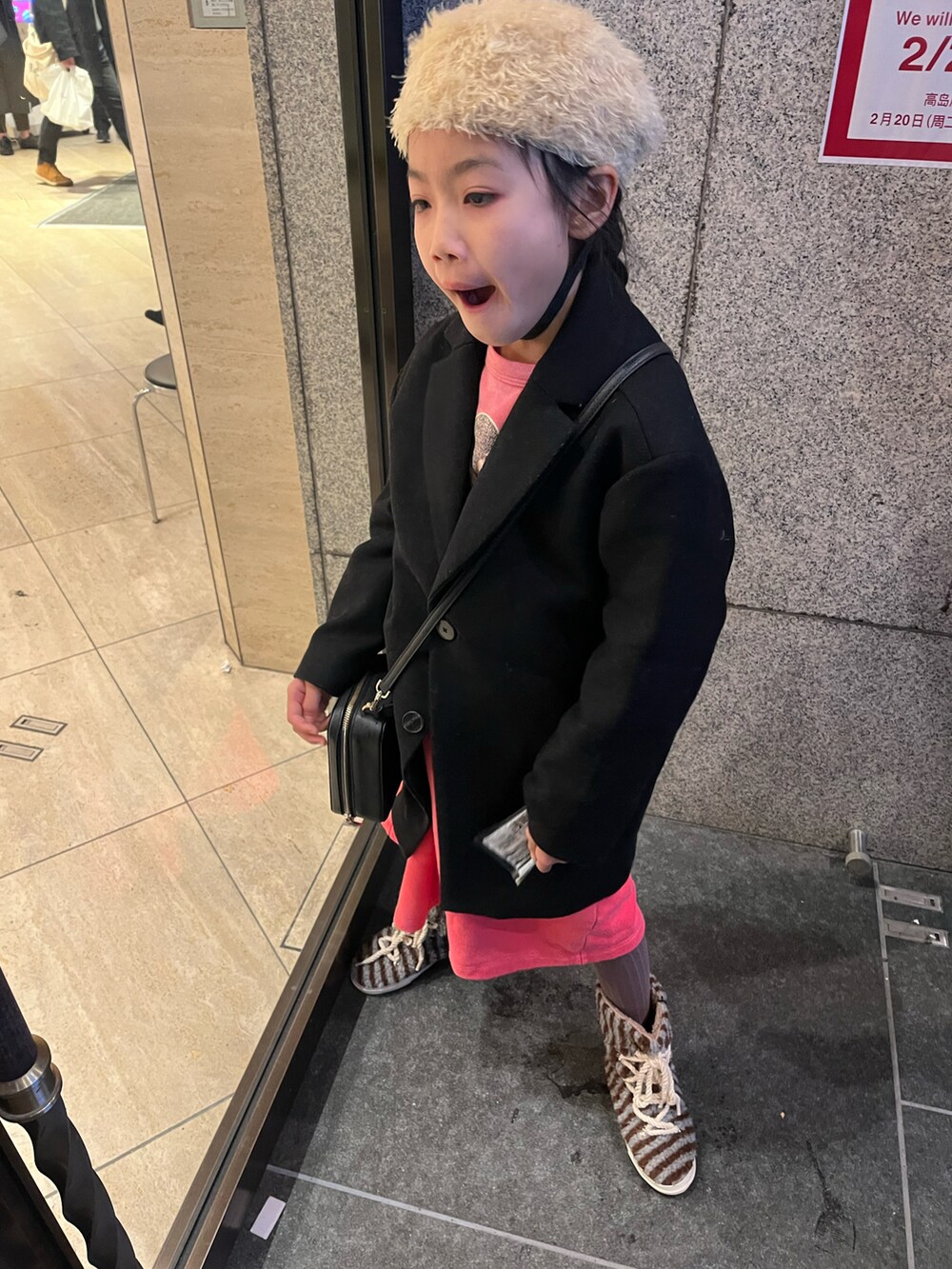 ブラック系のチェスターコート、ブルー系のブーツ、ブラック系のショルダーバッグを着用したキッズの冬コーディネートの2枚目の写真