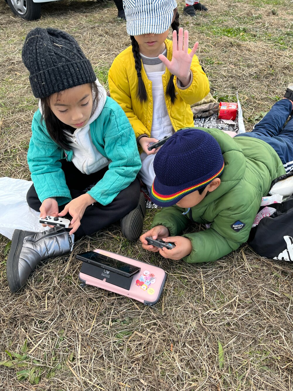 グリーン系のノーカラーコート、ベージュ系のスウェット、ブラック系のスウェットパンツを着用したキッズの冬コーディネートの3枚目の写真