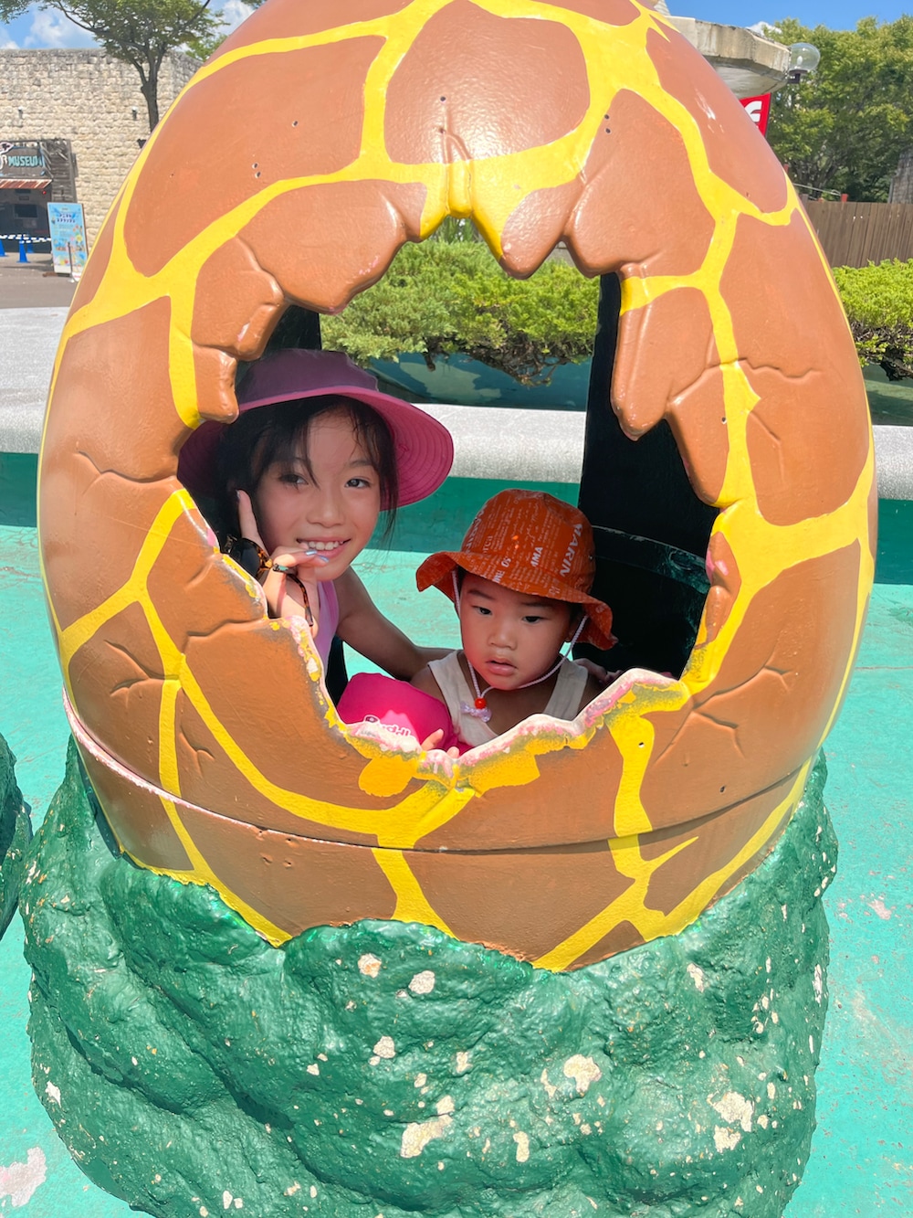 ブラック系のビーチサンダル、ピンク系のワンピース、ピンク系の帽子を着用したキッズの夏コーディネートの2枚目の写真