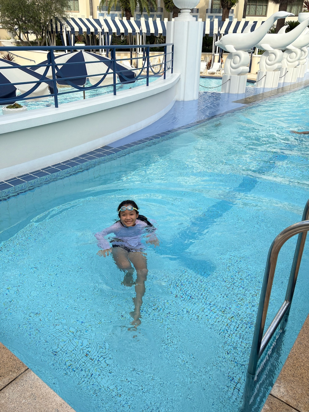 ピンク系のラッシュガード、ブラック系の水着を着用したキッズの夏コーディネートの3枚目の写真