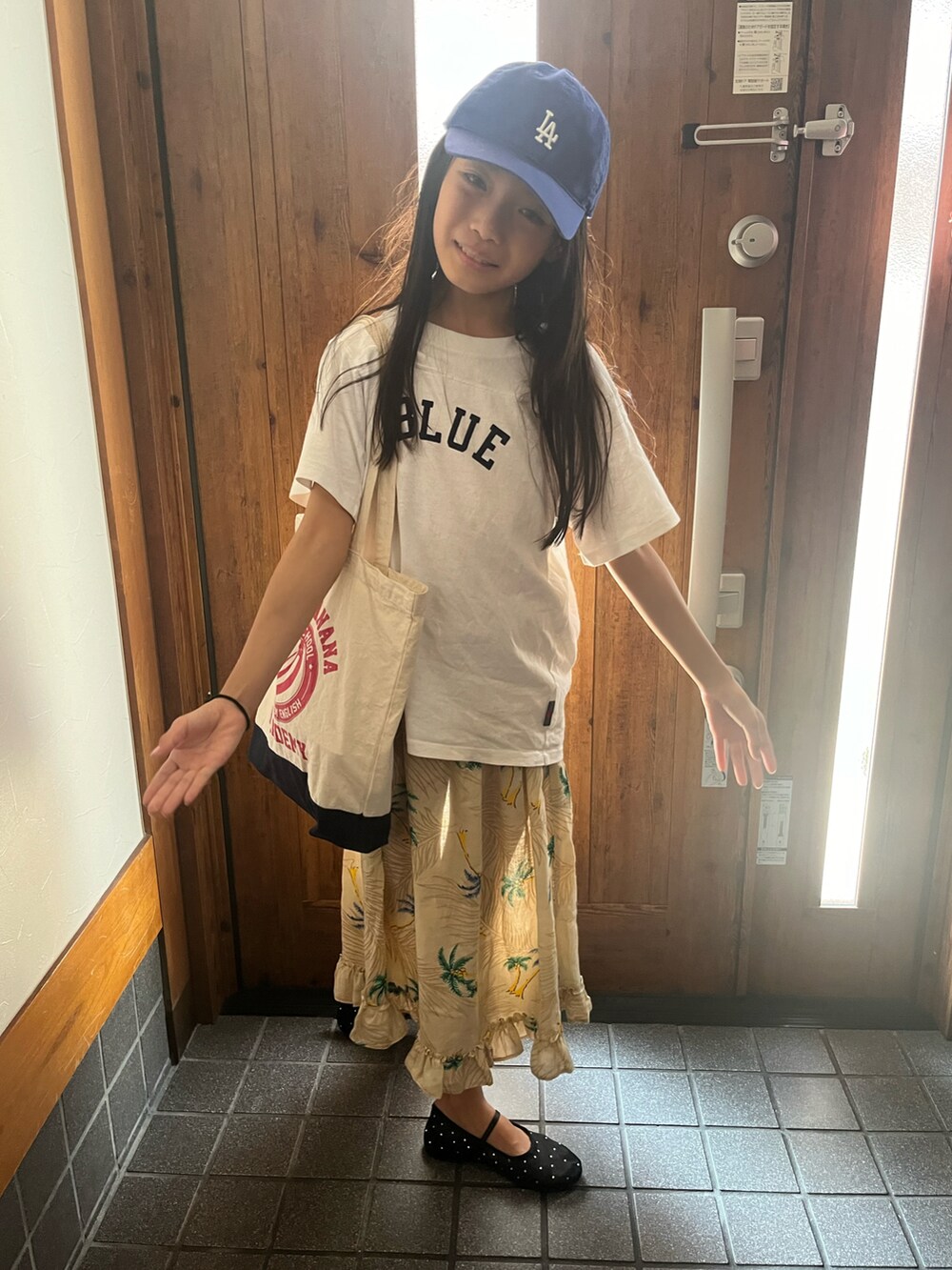 ホワイト系のTシャツ/カットソー、ベージュ系のワンピース、ブラック系のバレエシューズを着用したキッズの夏コーディネートの2枚目の写真