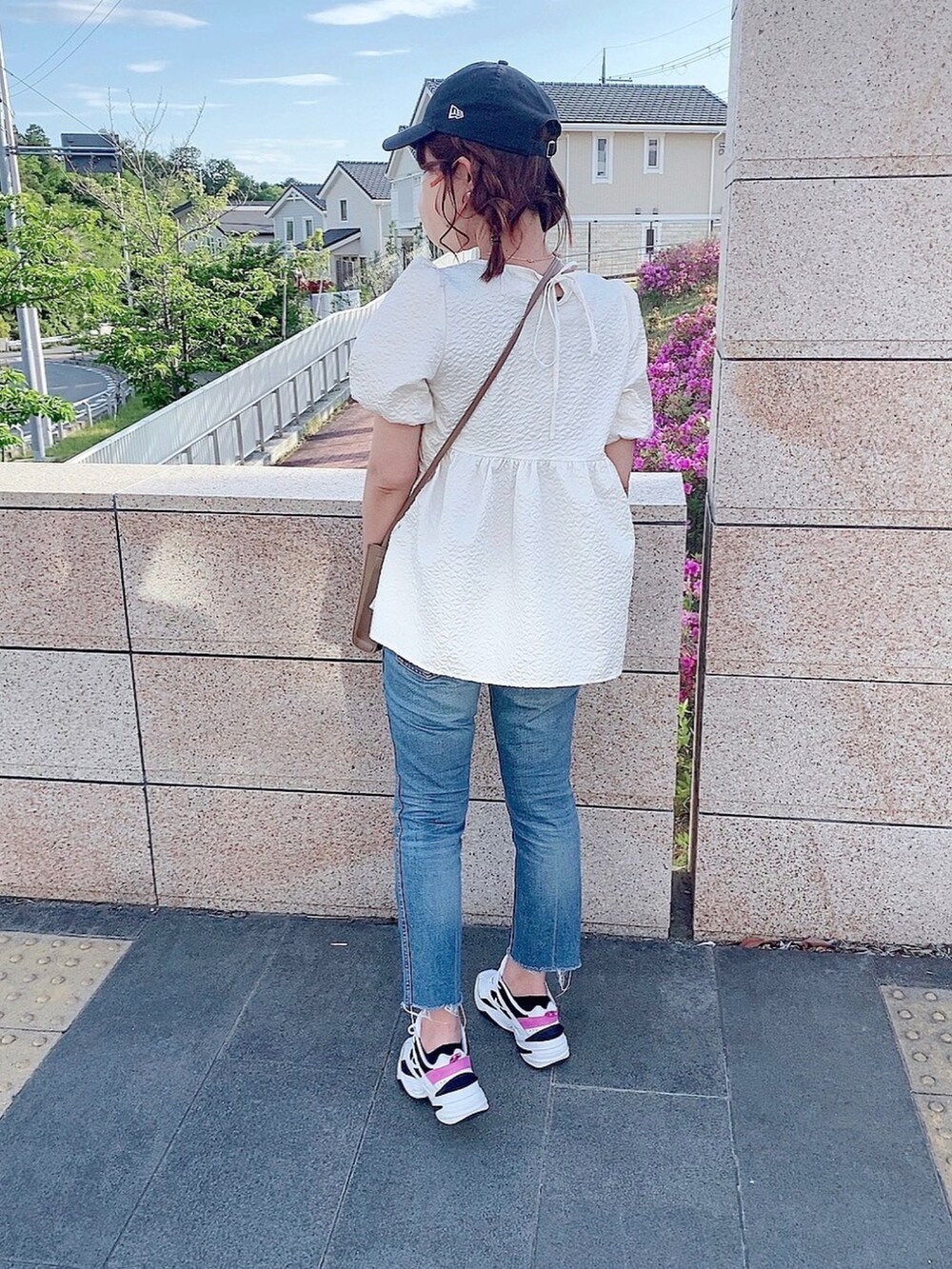 ブルー系のデニムパンツ、ベージュ系のショルダーバッグ、ホワイト系のTシャツ/カットソーを着用したレディースの春コーディネートの2枚目の写真