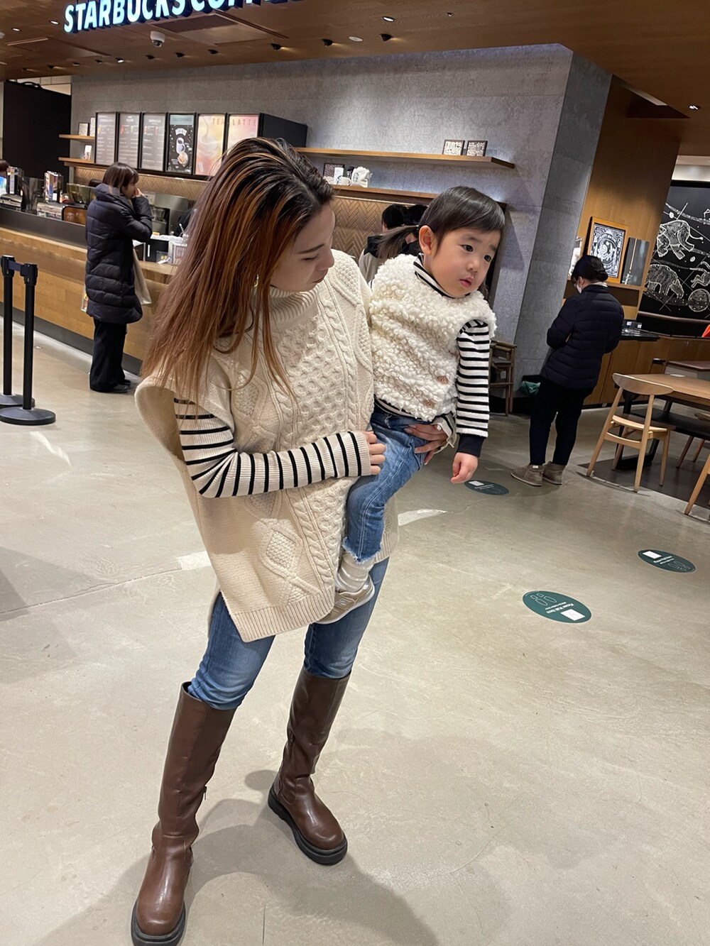 ホワイト系のベスト、ブルー系のデニムパンツ、ベージュ系のスニーカーを着用したキッズの冬コーディネートの2枚目の写真