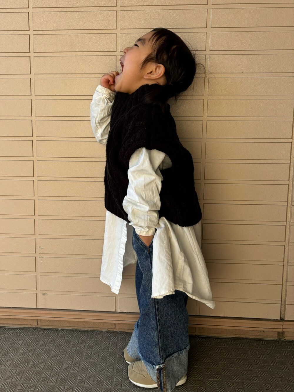 ブラック系のベスト、ホワイト系のシャツ/ブラウス、ブルー系のデニムパンツを着用したキッズの冬コーディネートの2枚目の写真