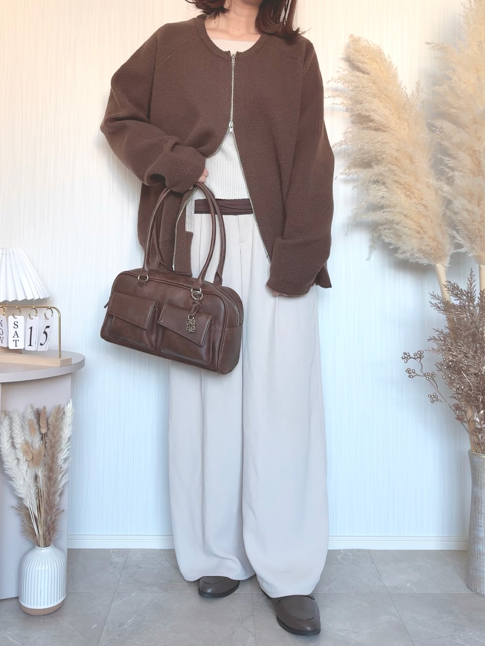ブラウン系のショルダーバッグを着用したレディースの秋コーディネートの2枚目の写真