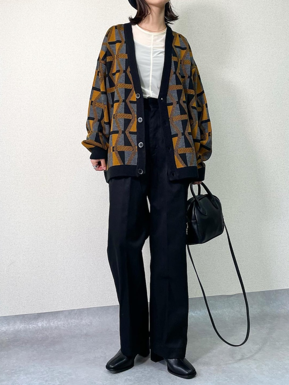 ブラック系のブーツ、イエロー系のカーディガン/ボレロ、ブラック系のその他パンツを着用したレディースの秋コーディネートの2枚目の写真