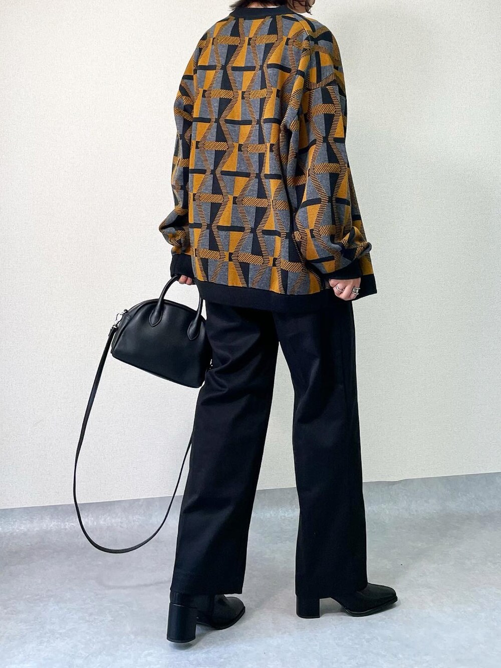 ブラック系のブーツ、イエロー系のカーディガン/ボレロ、ブラック系のその他パンツを着用したレディースの秋コーディネートの3枚目の写真