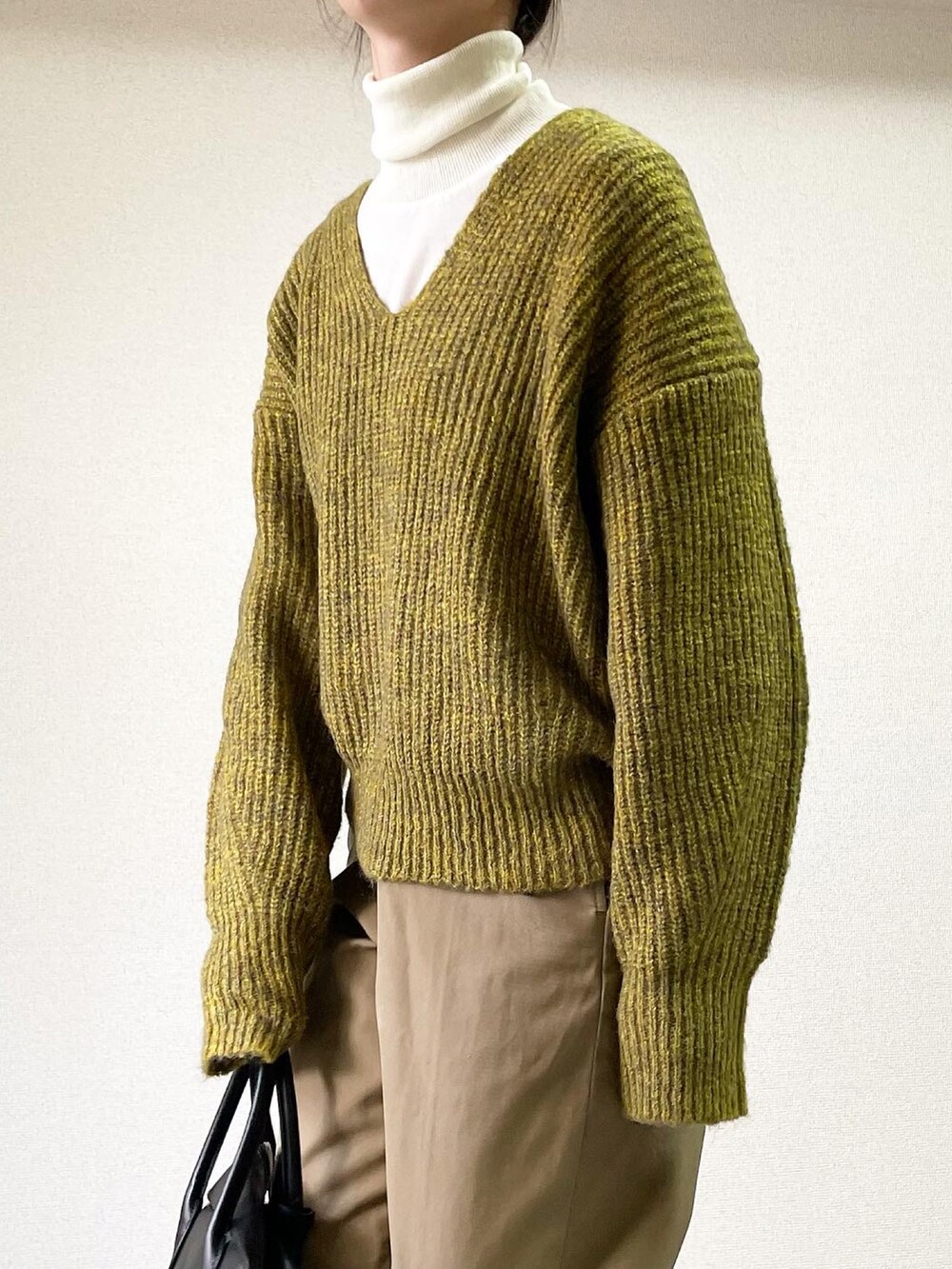 ブラウン系のステンカラーコート、イエロー系のニット/セーター、ベージュ系のチノパンツを着用したレディースの冬コーディネートの3枚目の写真