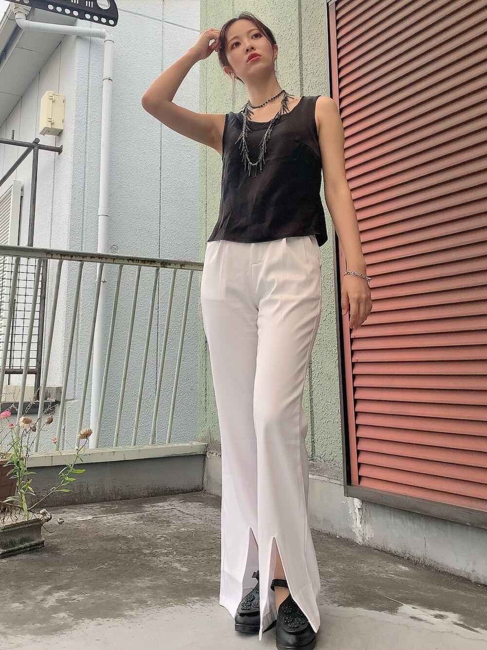 ブラック系のタンクトップ、ブルー系のデニムジャケット、ホワイト系のスラックスを着用したレディースの夏コーディネートの2枚目の写真