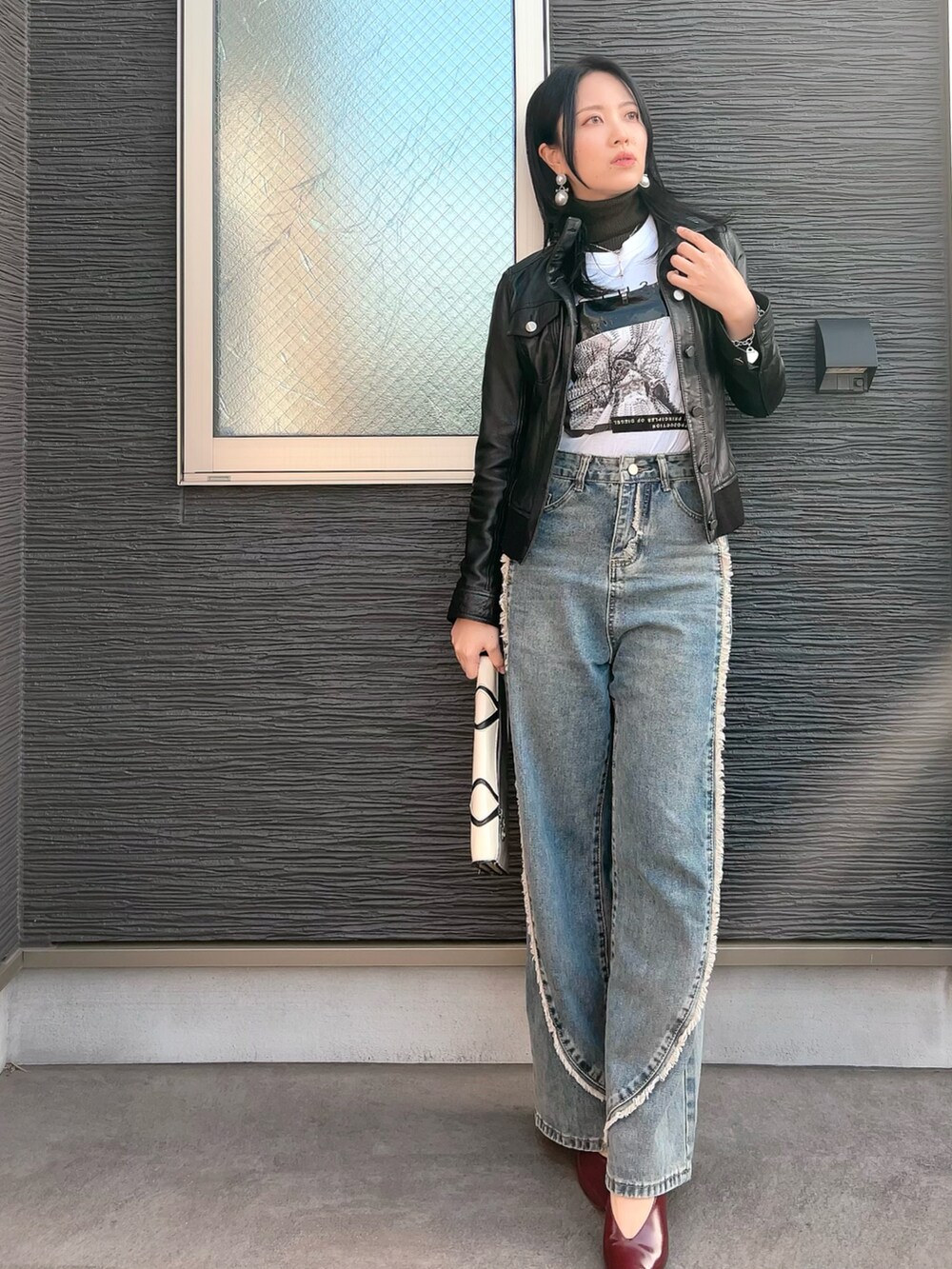 ブラック系のライダースジャケット、グリーン系のニット/セーター、ホワイト系のTシャツ/カットソーを着用したレディースの春コーディネートの2枚目の写真