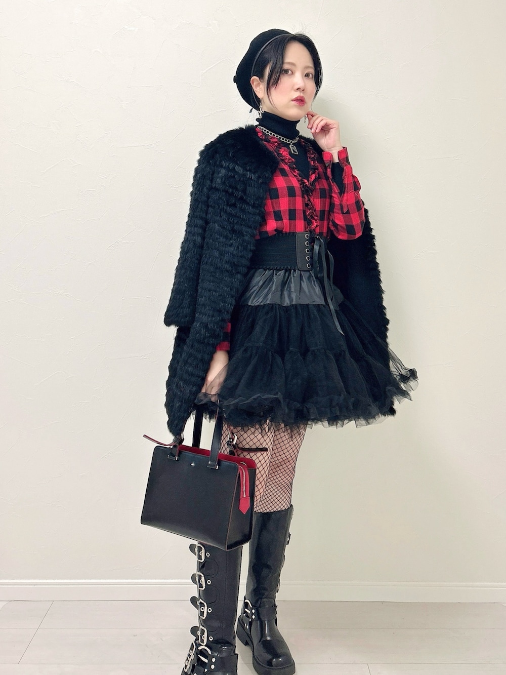 ブラック系のニット/セーター、レッド系のシャツ/ブラウス、ブラック系のスカートを着用したレディースの冬コーディネートの2枚目の写真