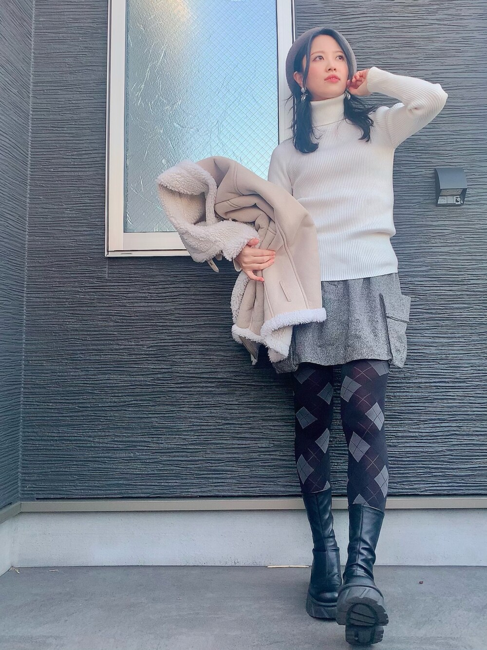 ホワイト系のニット/セーター、ベージュ系のムートンコート、グレー系のスカートを着用したレディースの冬コーディネートの2枚目の写真