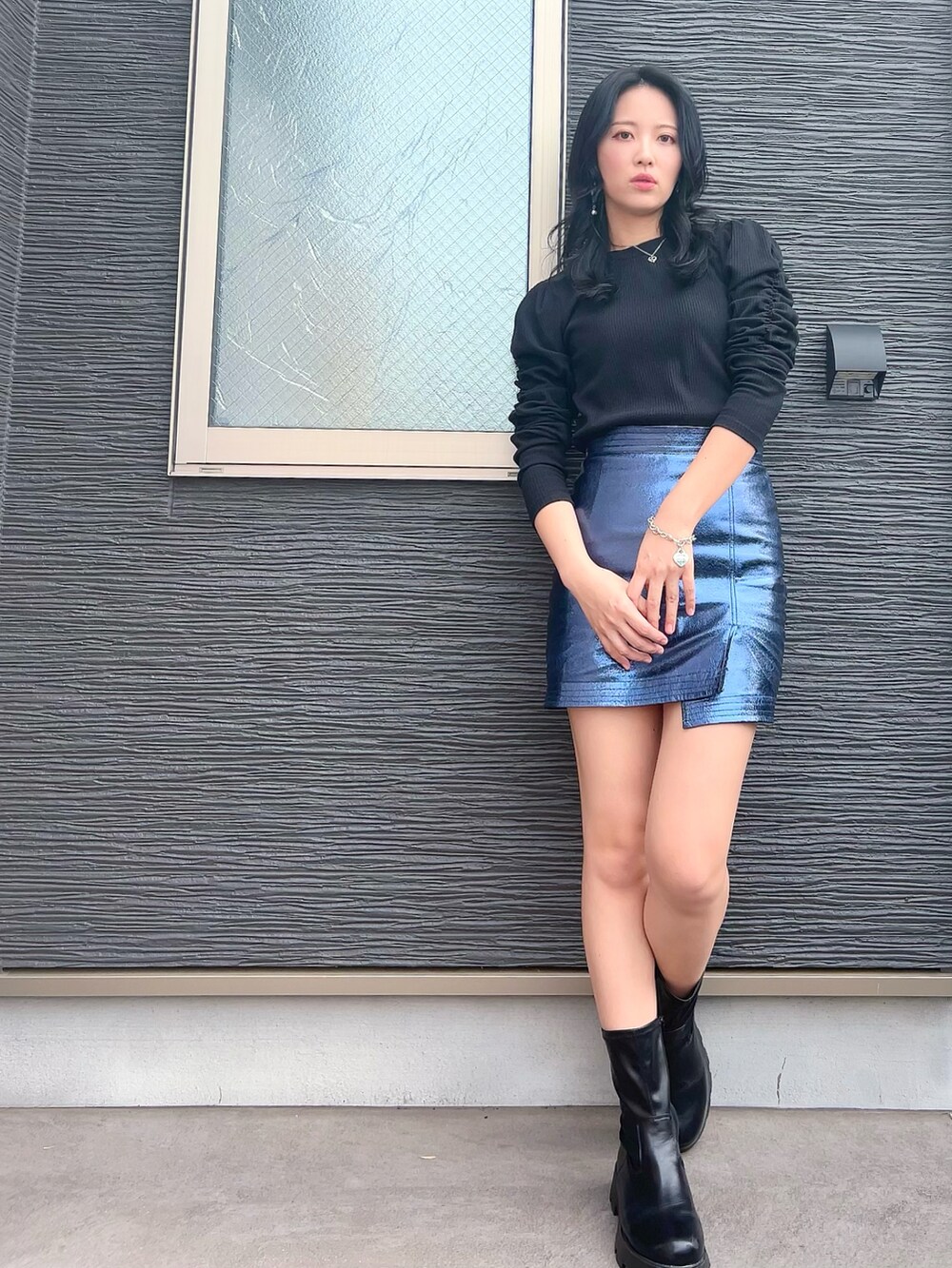 ブラック系のライダースジャケット、ブルー系のスカート、ブラック系のブーツを着用したレディースの春コーディネートの2枚目の写真