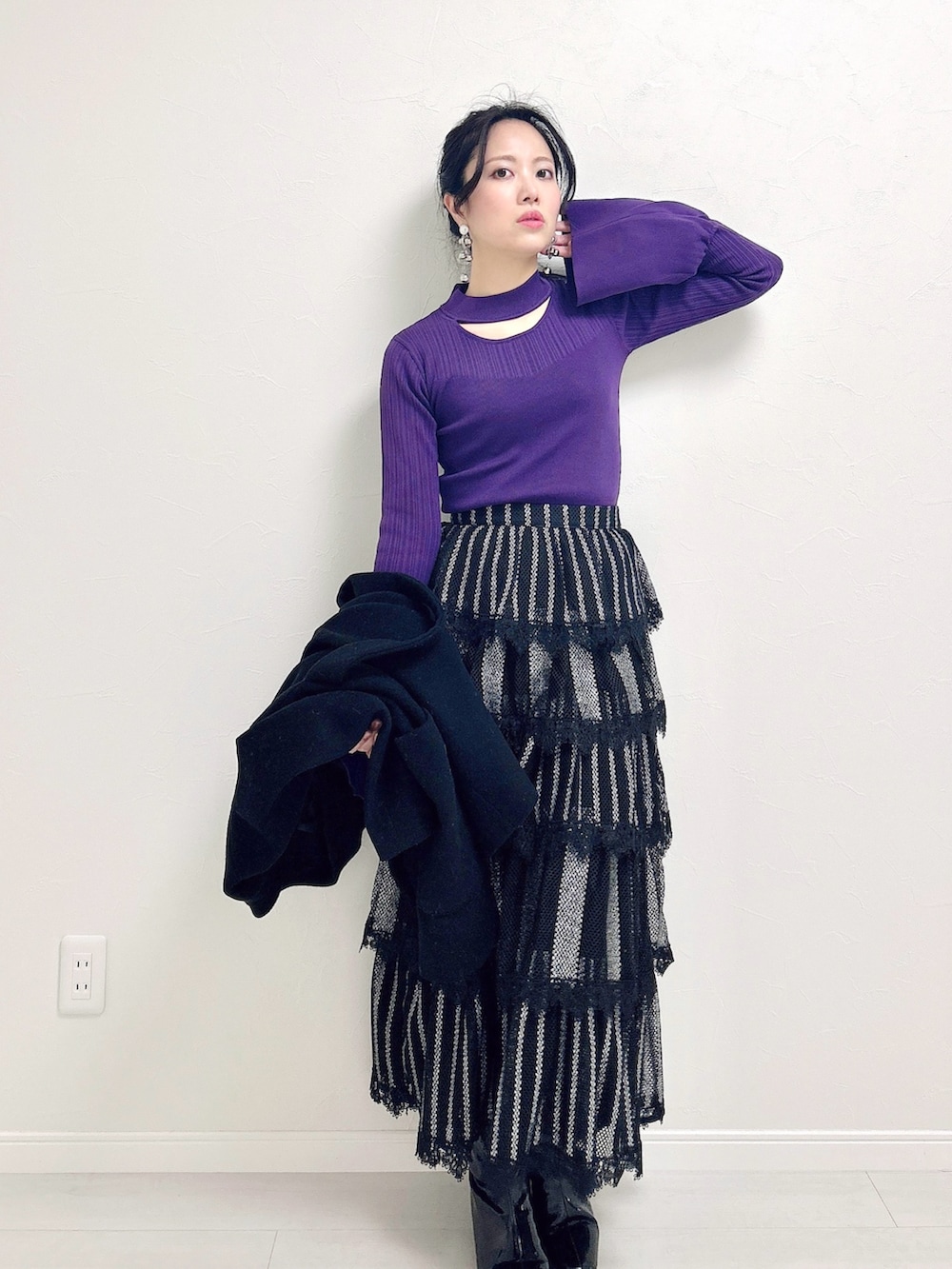 パープル系のニット/セーター、ブラック系のスカート、ブラック系のブーツを着用したレディースの冬コーディネートの2枚目の写真