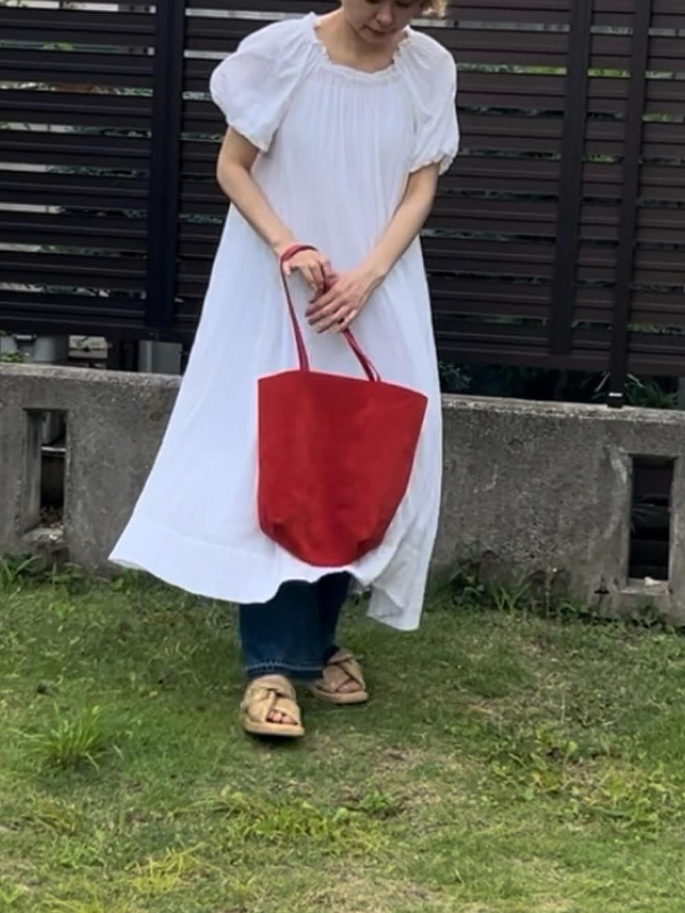 ホワイト系のワンピース、ブルー系のデニムパンツ、ベージュ系のサンダルを着用したレディースの夏コーディネートの2枚目の写真