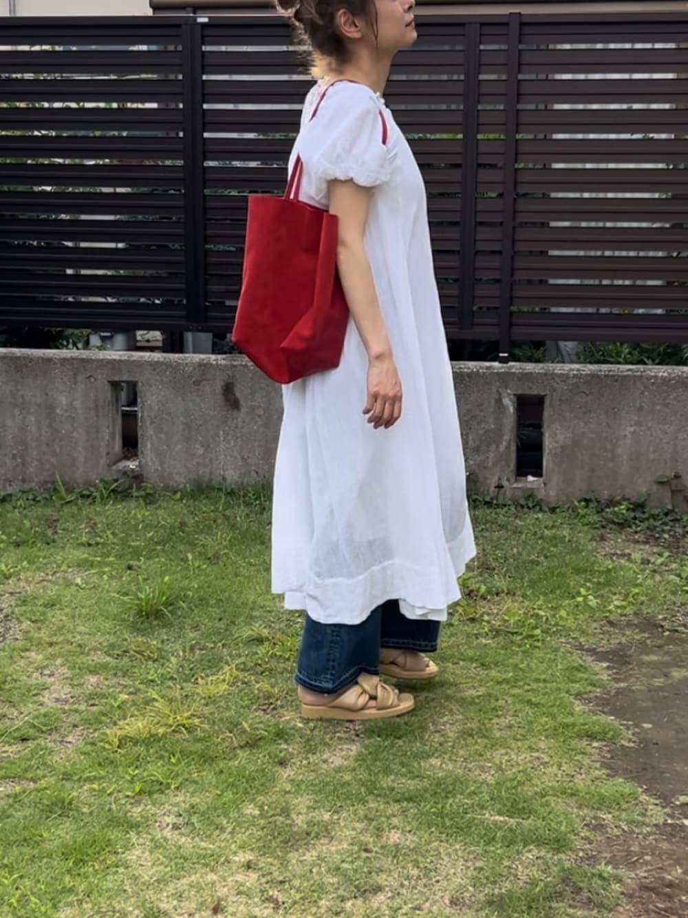 ホワイト系のワンピース、ブルー系のデニムパンツ、ベージュ系のサンダルを着用したレディースの夏コーディネートの3枚目の写真