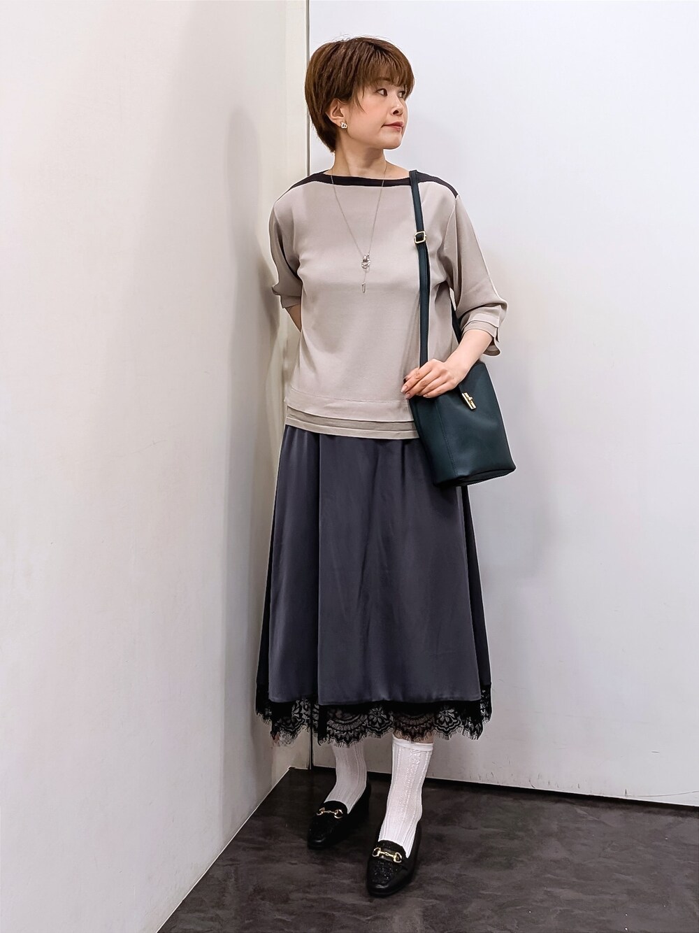ベージュ系のニット/セーター、ホワイト系のTシャツ/カットソー、ブルー系のスカートを着用したレディースの秋コーディネートの5枚目の写真