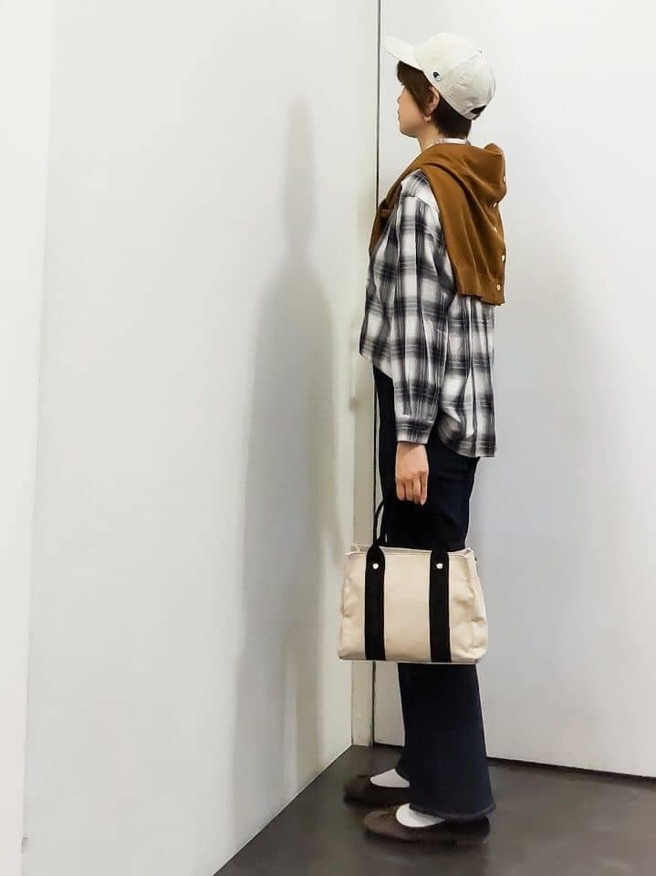 イエロー系のカーディガン/ボレロ、ホワイト系のシャツ/ブラウス、ブラック系のタンクトップを着用したレディースの秋コーディネートの2枚目の写真
